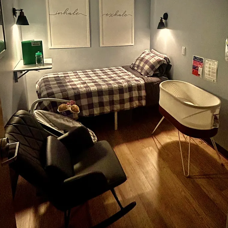A private room at Hushabye Nursery: a bed for a parent, a bassinet and a rocking chair in low light